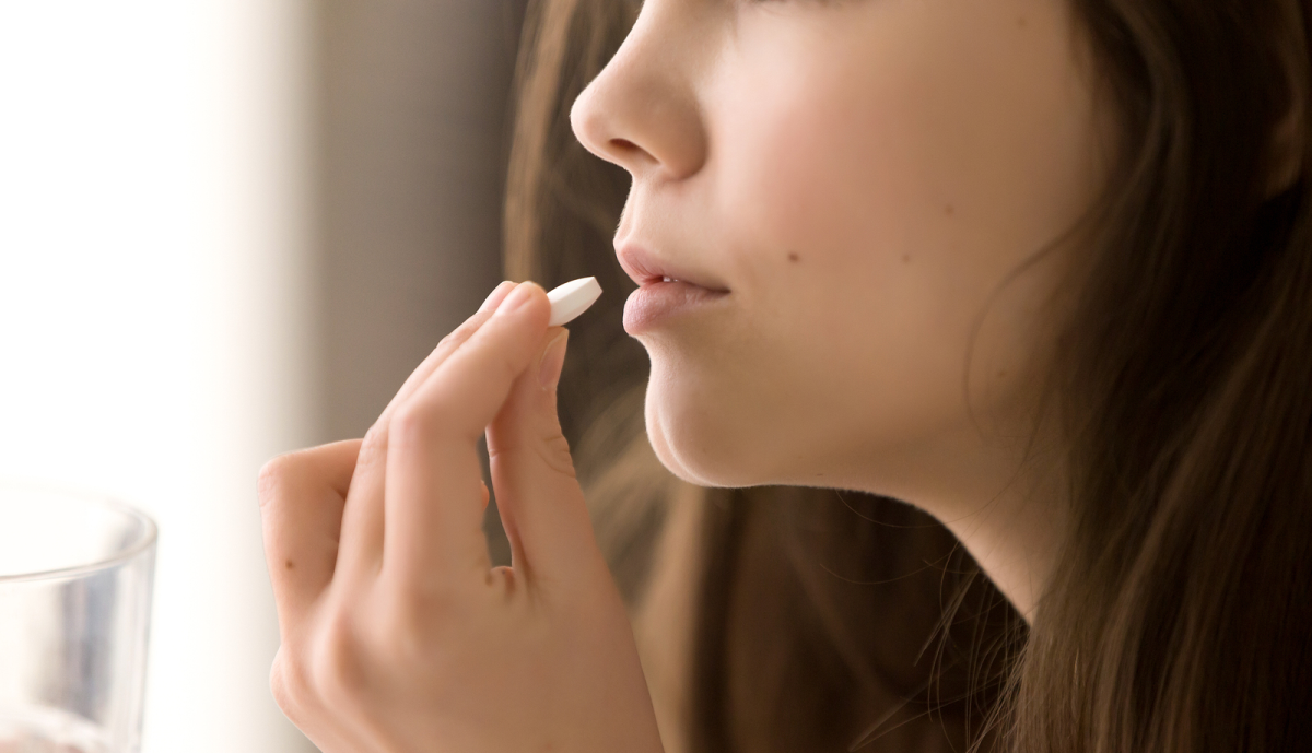 Mulher tomando comprimido para hormonioterapia